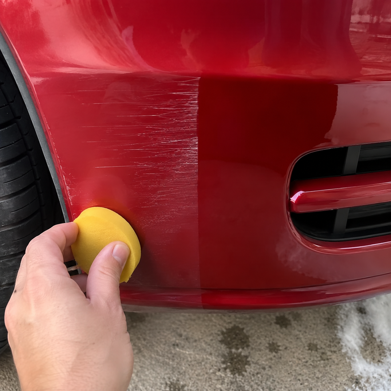 Customer polishing a light scratch on red car paint